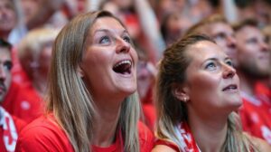 Female ice hockey fans cheering in arena stands.